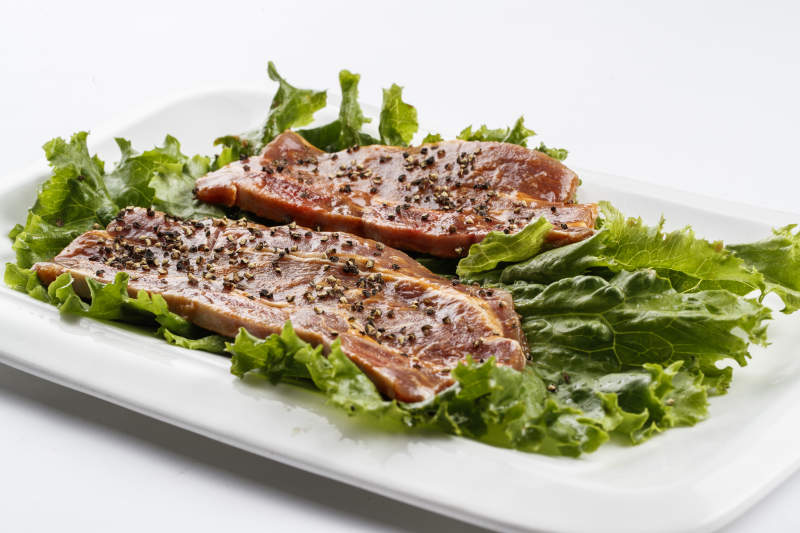 长方形白瓷盘装的黑胡椒腌制牛排肉图片