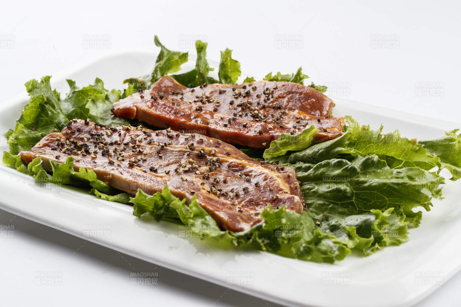 长方形白瓷盘装的黑胡椒腌制牛排肉图片