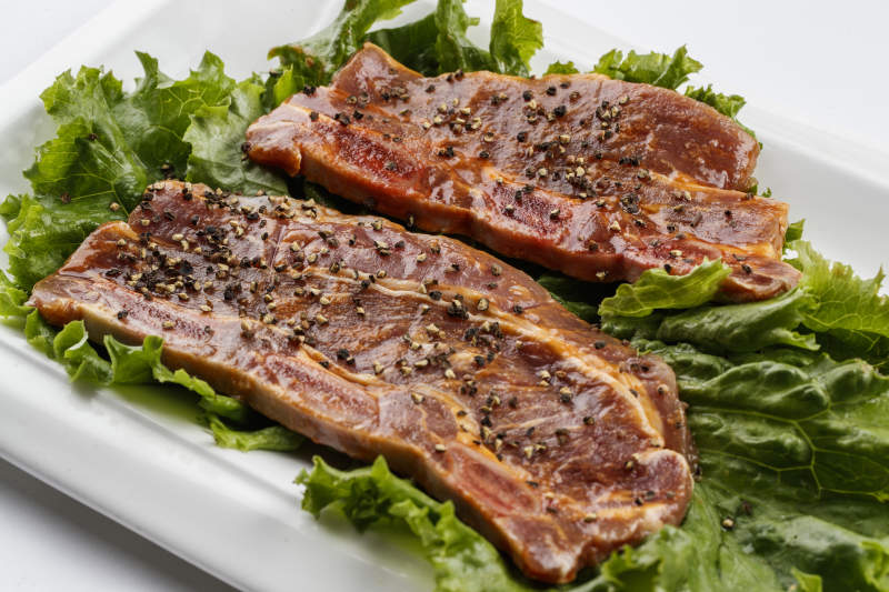 长方形白瓷盘装的黑胡椒腌制牛排肉图片