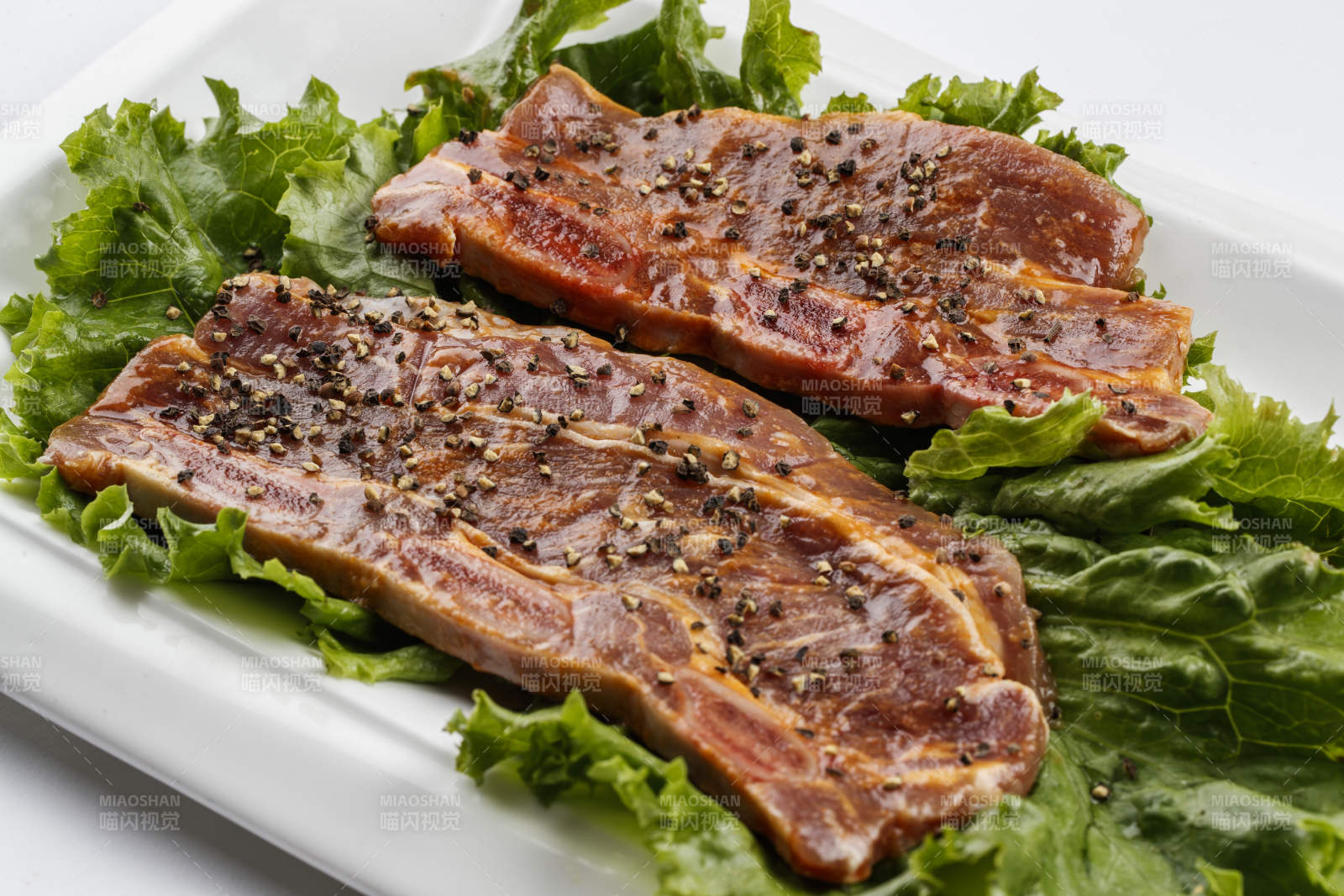 长方形白瓷盘装的黑胡椒腌制牛排肉图片