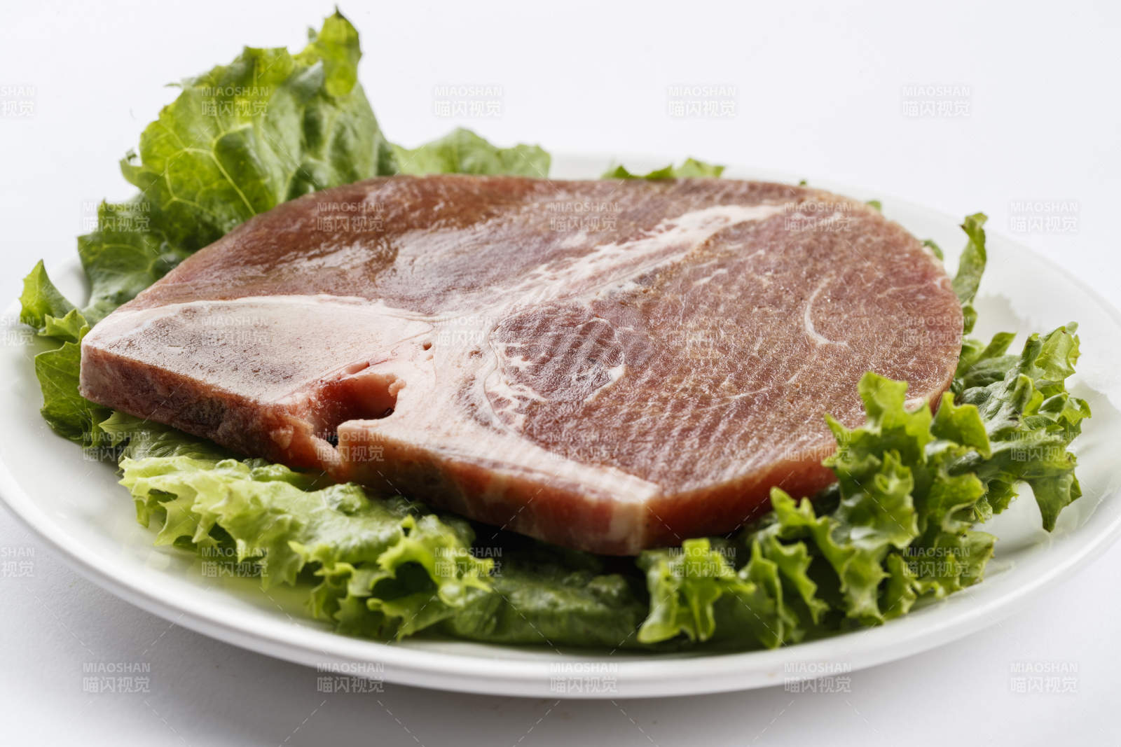 圆形白色瓷盘装的T骨牛排图片