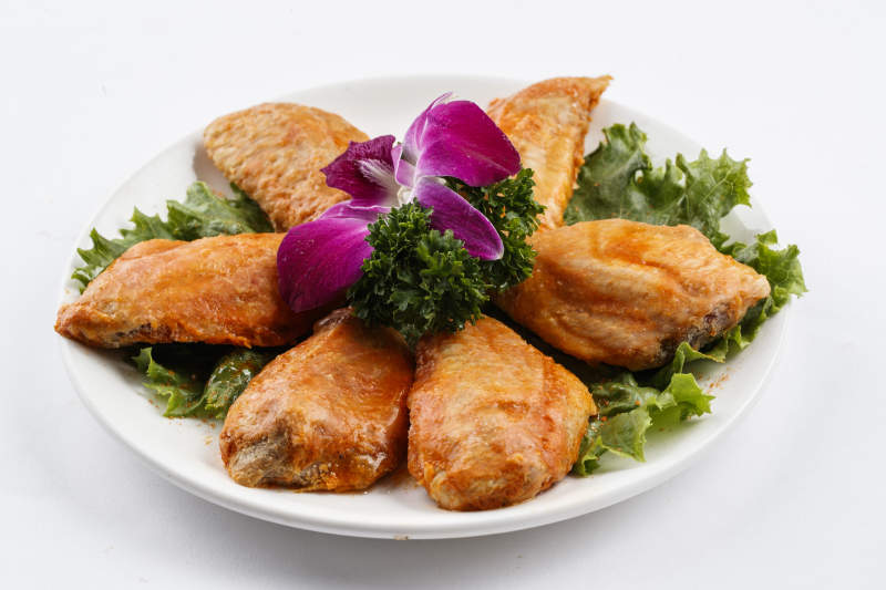 圆形白瓷盘装的腌制鸡翅中图片