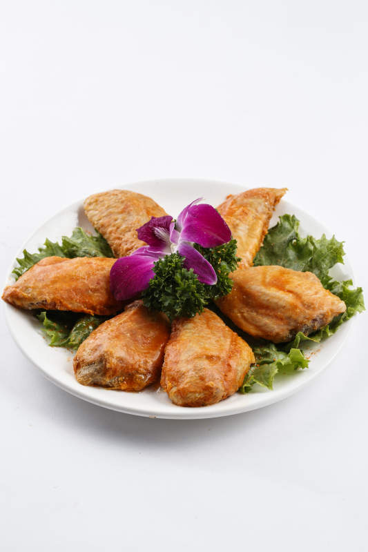 圆形白瓷盘装的腌制鸡翅中图片