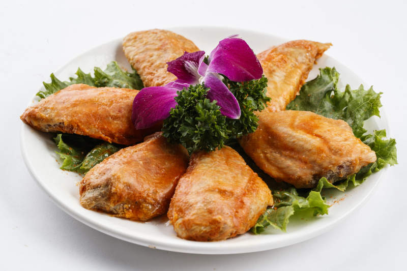 圆形白瓷盘装的腌制鸡翅中图片