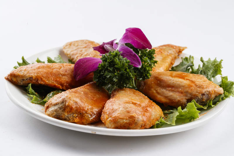 圆形白瓷盘装的腌制鸡翅中图片