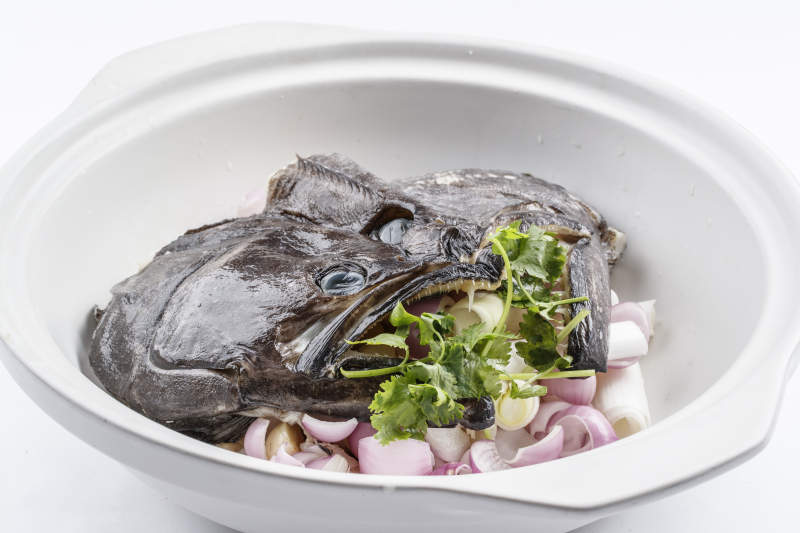 陈旧木板上的黑色砂锅装的浓汤生噘鲽鱼图片