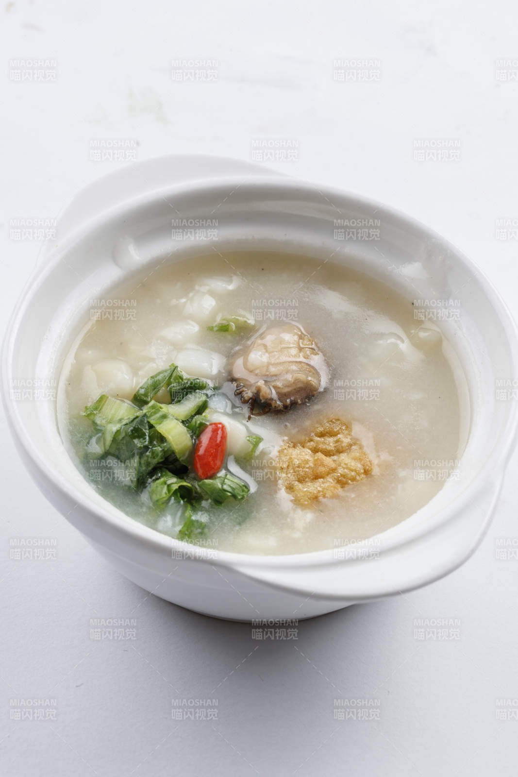 白色瓷碗装的鲜鲍鱼小白菜粥图片