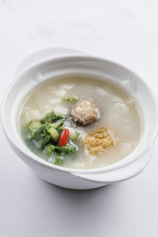 白色瓷碗装的鲜鲍鱼小白菜粥图片