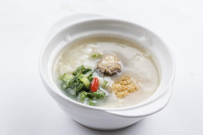 白色瓷碗装的鲜鲍鱼小白菜粥图片
