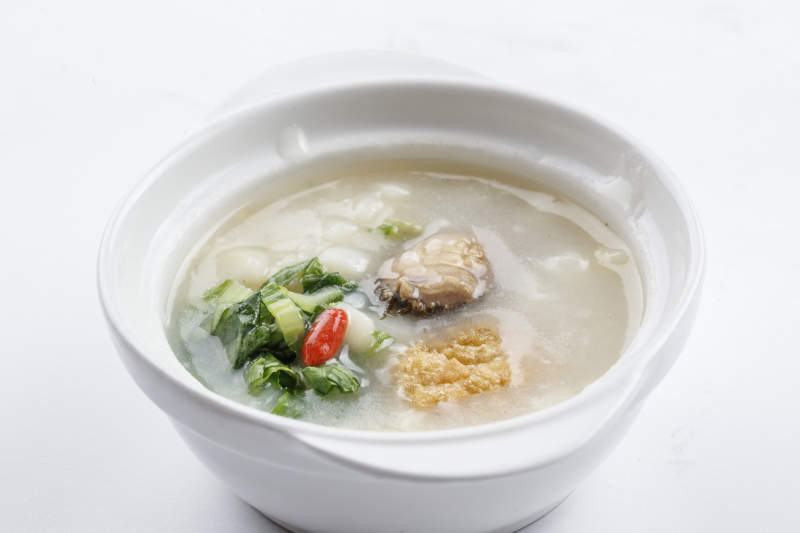白色瓷碗装的鲜鲍鱼小白菜粥图片