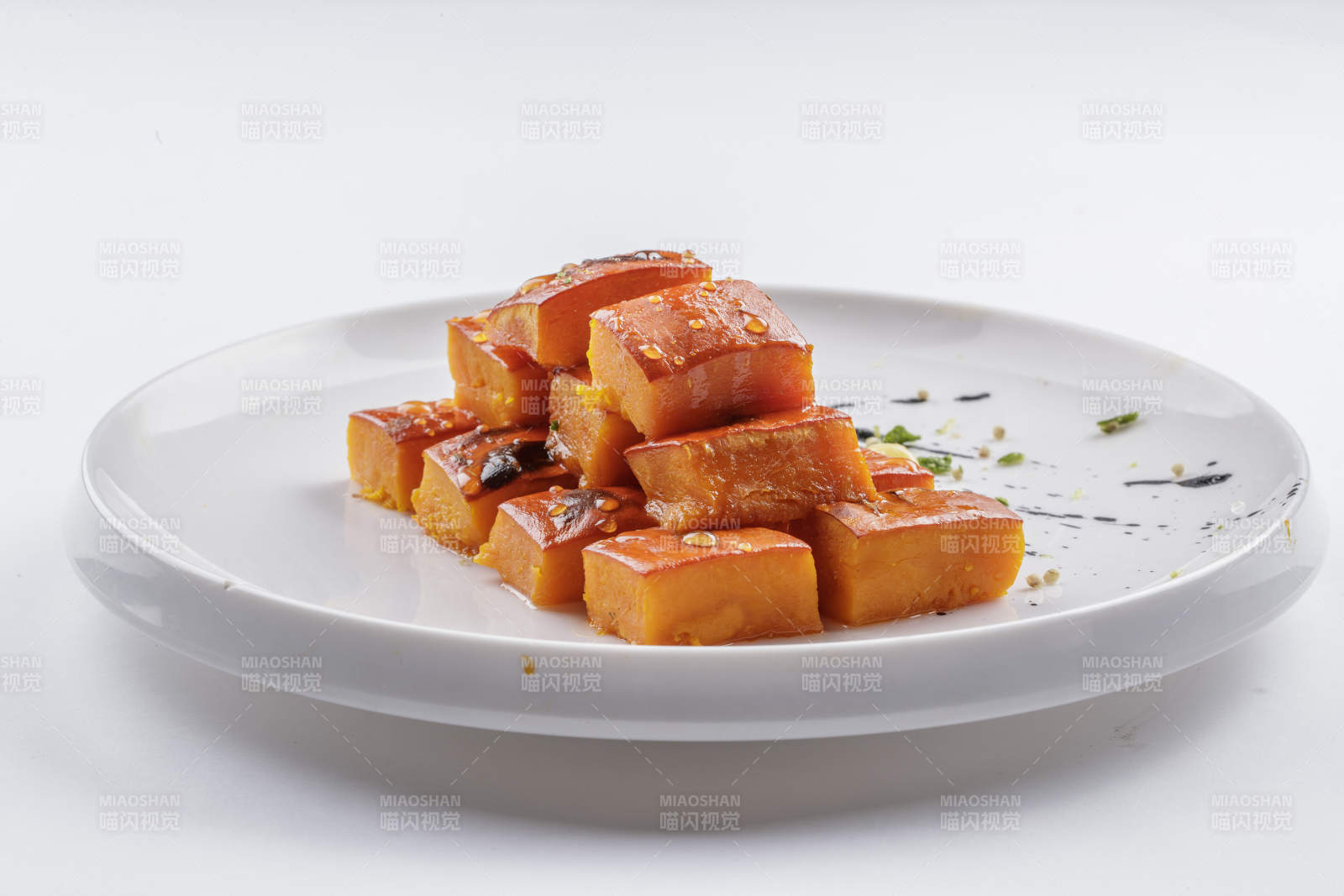 青瓷盘装的蜂蜜焗南瓜摆放在白色背景上图片