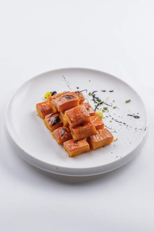 青瓷盘装的蜂蜜焗南瓜摆放在白色背景上图片