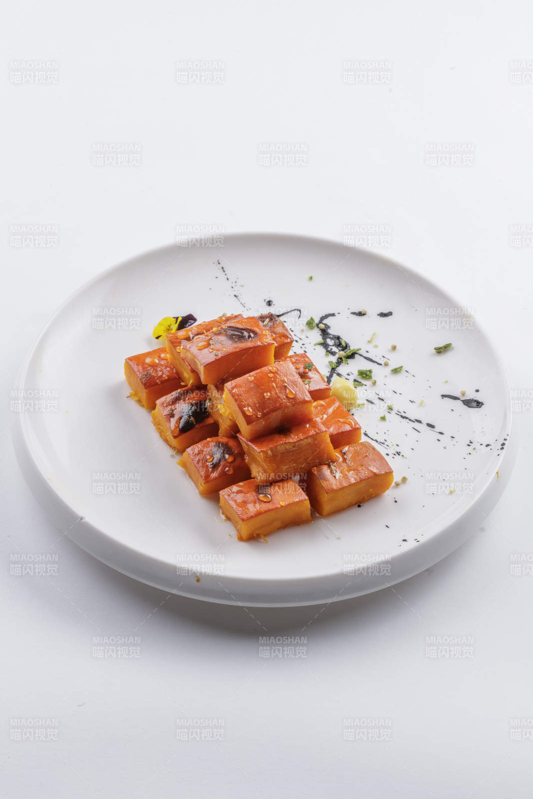 青瓷盘装的蜂蜜焗南瓜摆放在白色背景上图片