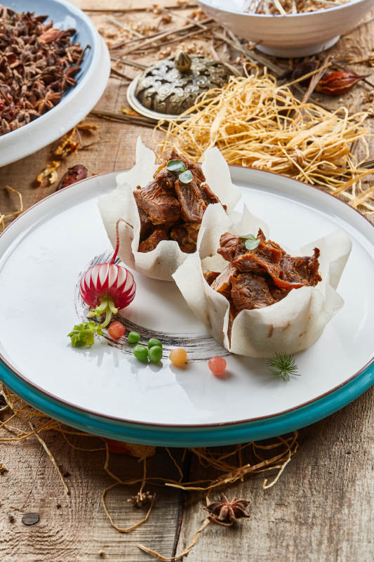 双色圆瓷盘装的佛手酱牛腱子肉图片