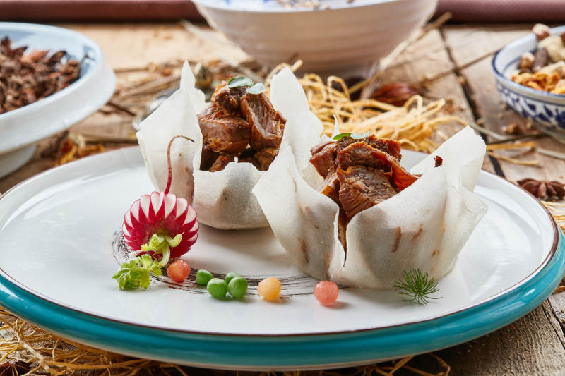 双色圆瓷盘装的佛手酱牛腱子肉图片