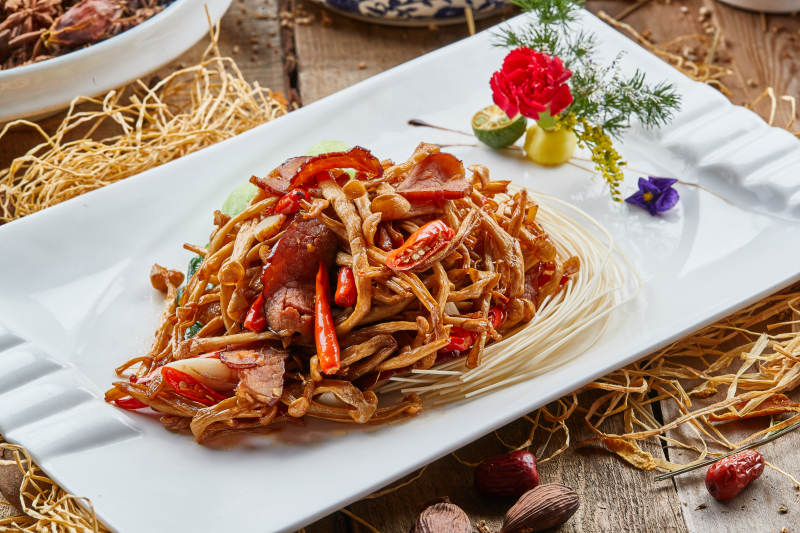白色瓷盘的茶树菇蒜香炒腊肉图片