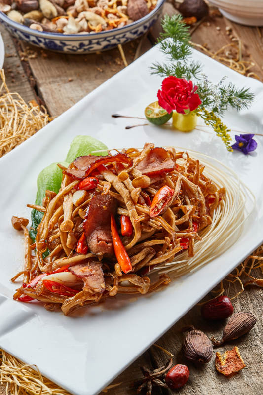 白色瓷盘的茶树菇蒜香炒腊肉图片