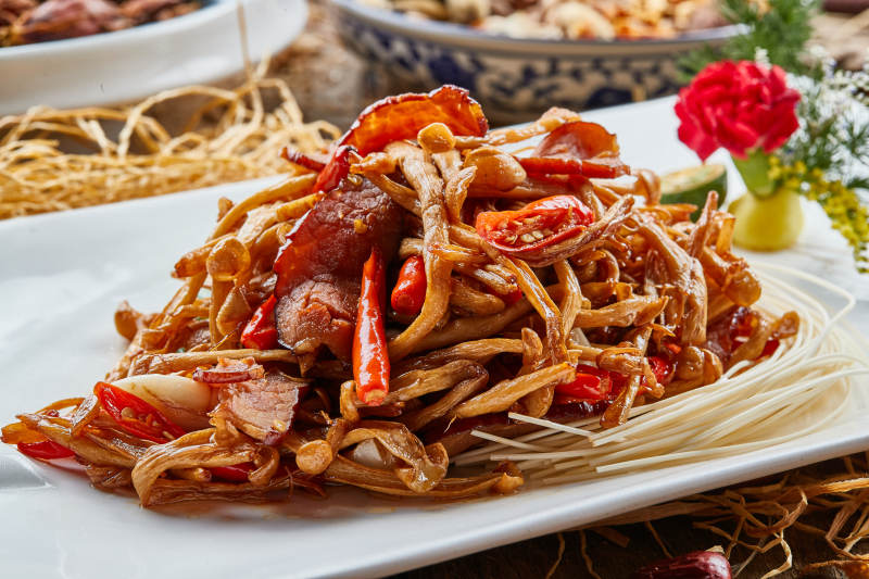 白色瓷盘的茶树菇蒜香炒腊肉图片