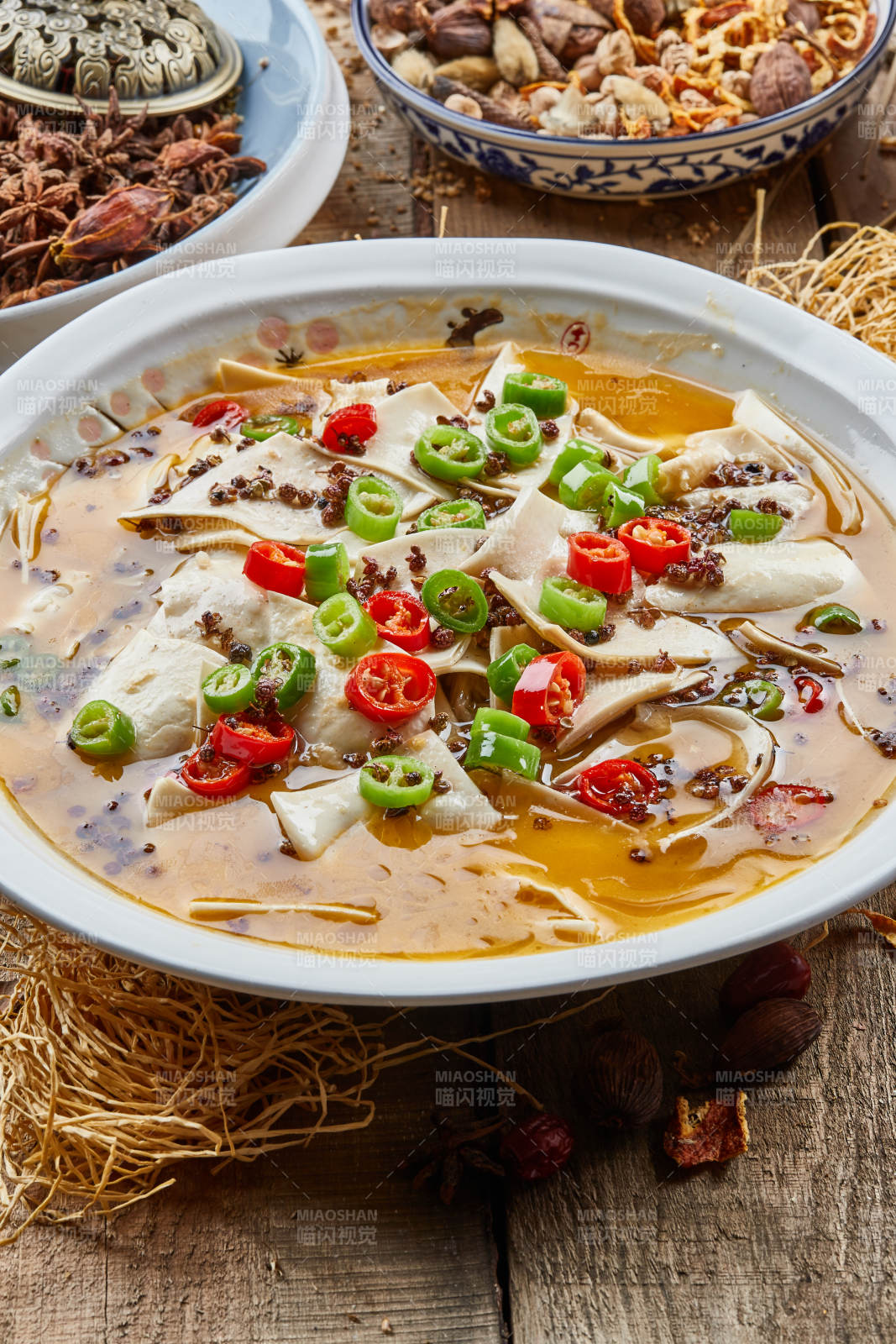 青瓷汤盆装的酸汤黄喉摆放在陈旧木板上图片