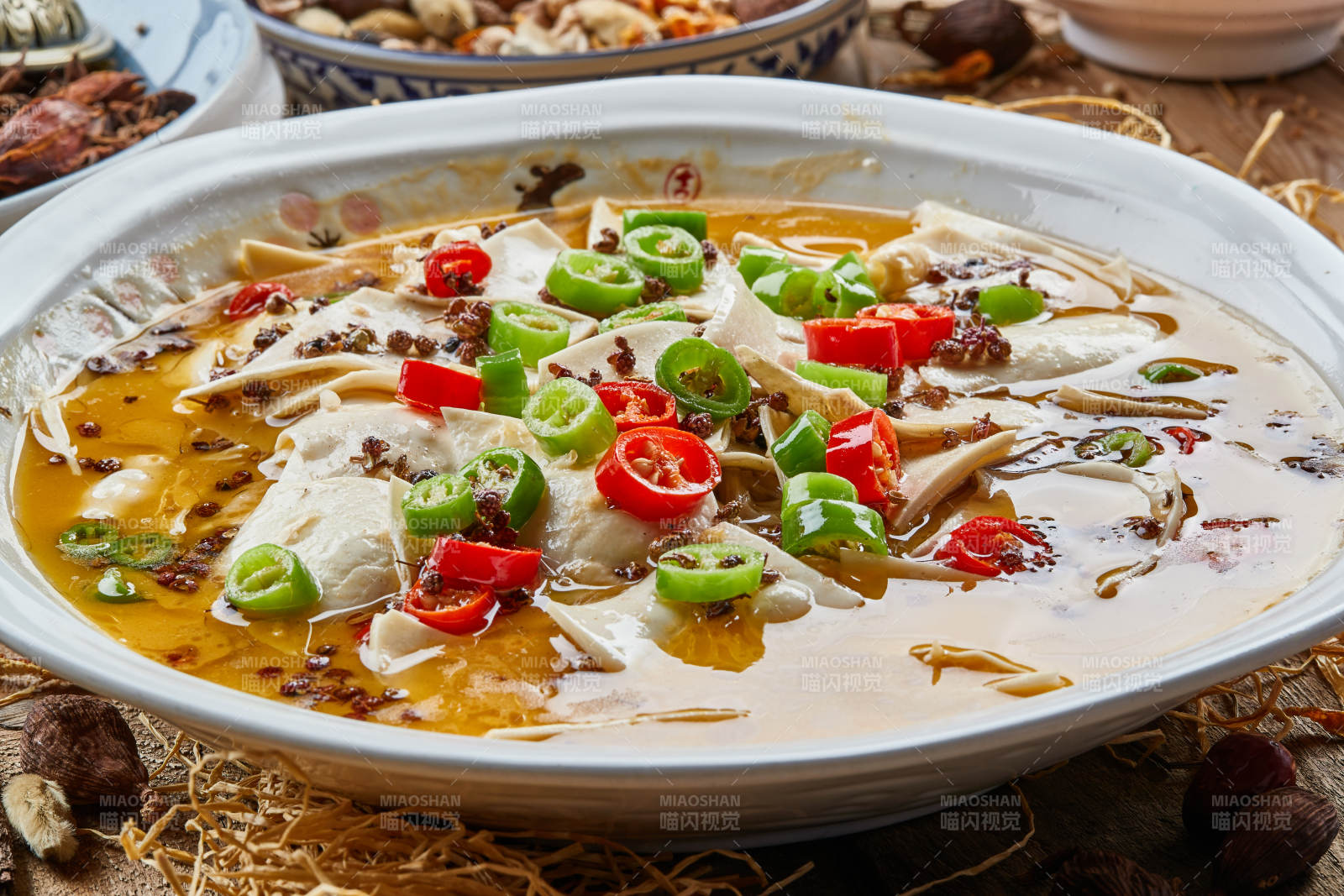 青瓷汤盆装的酸汤黄喉摆放在陈旧木板上图片