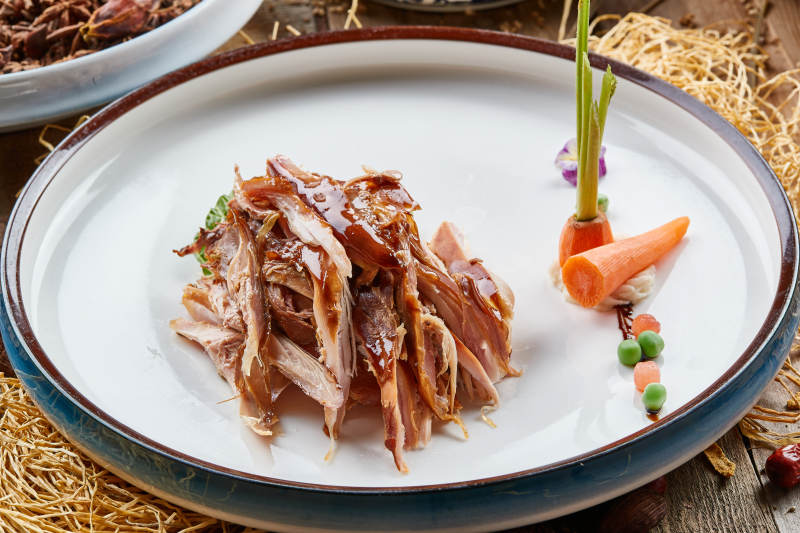 双色圆瓷盘装的手撕兔图片