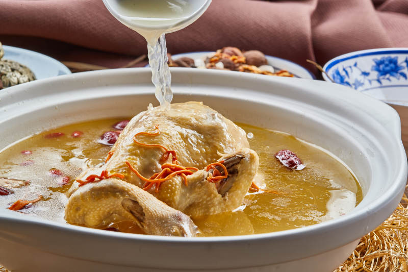 白色砂锅装的红枣虫草枸杞参鸡汤图片