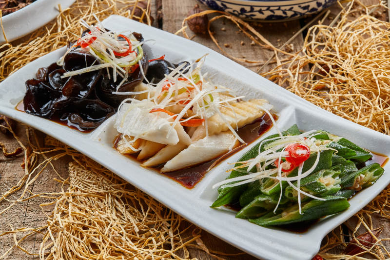 三格瓷盘装的酸辣小菜木耳山药秋葵图片