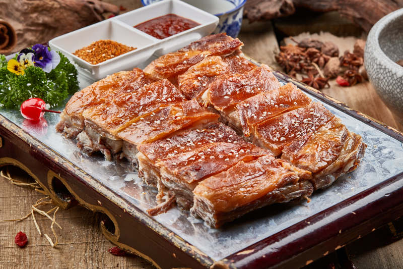 红色漆盘装的蒙古烤羊排摆放在樟木砧板上图片