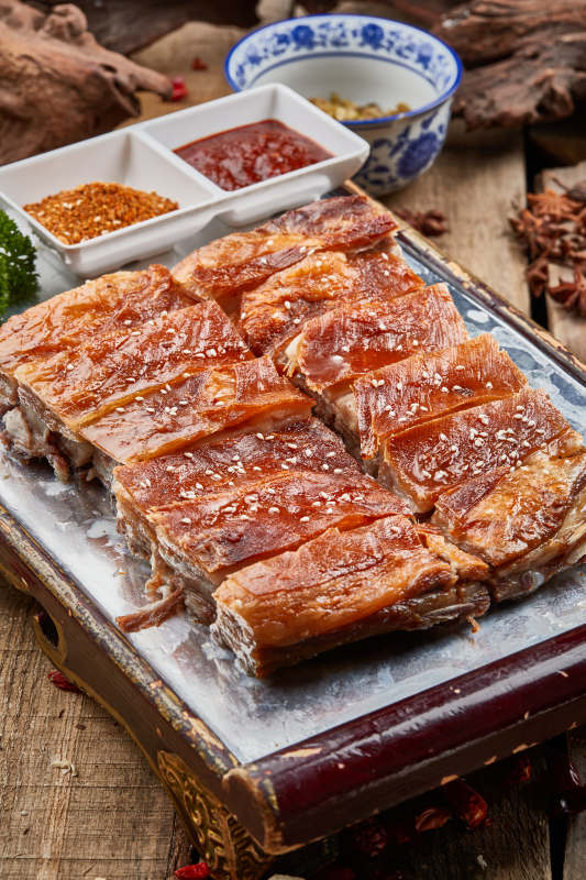 红色漆盘装的蒙古烤羊排摆放在樟木砧板上图片