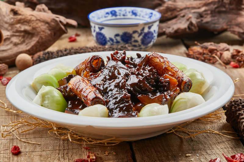 葱烧梅花参摆放在黑色背景上图片