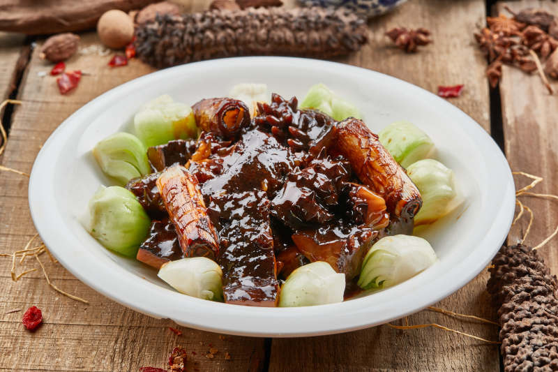 葱烧梅花参摆放在黑色背景上图片