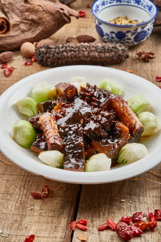 葱烧梅花参摆放在黑色背景上图片