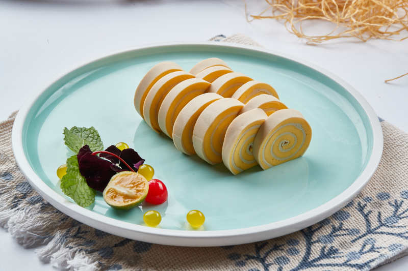 白色瓷盘组昂的豆腐皮熏肉卷切片图片