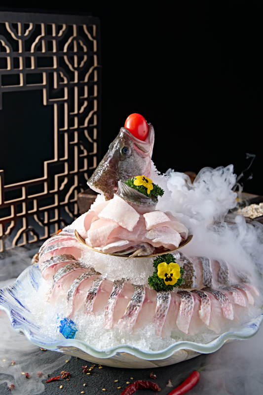 布满碎冰的青色瓷盘装的海鲈鱼刺身生鱼片图片