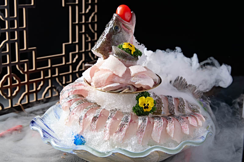 布满碎冰的青色瓷盘装的海鲈鱼刺身生鱼片图片