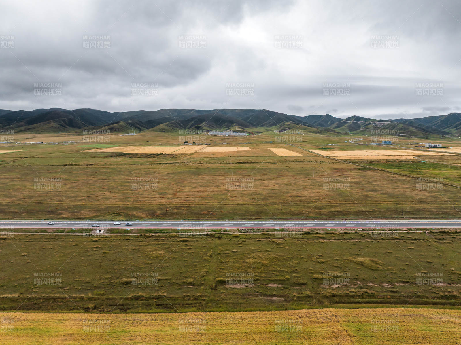 草原蜿蜒公路远景山脉农田自然风光阴云密布图片