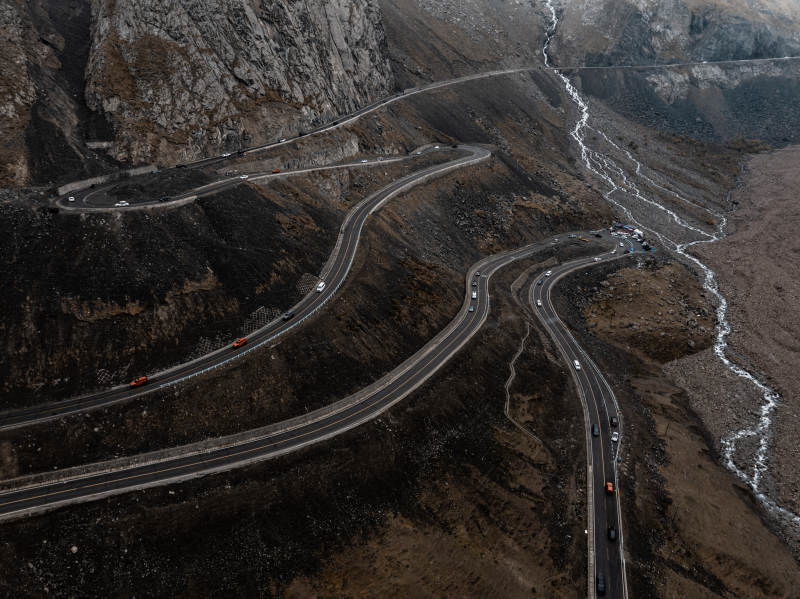 俯拍蜿蜒公路穿行岩壁河床的荒凉山地景致图片