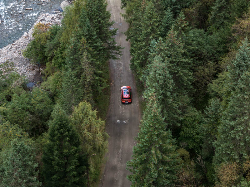 红色汽车在山林溪流边穿越原始森林越野自驾图片