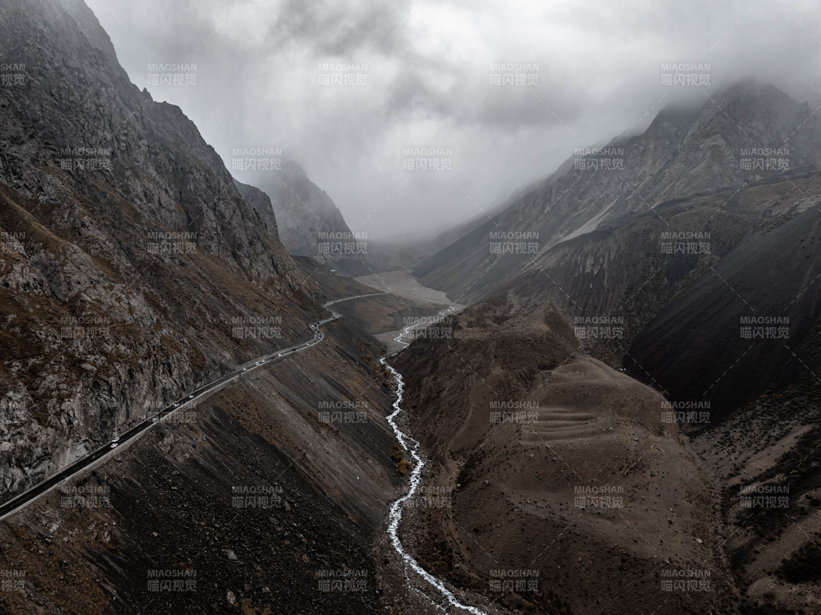 云雾山谷中蜿蜒公路与溪流相映的静谧自然景图片