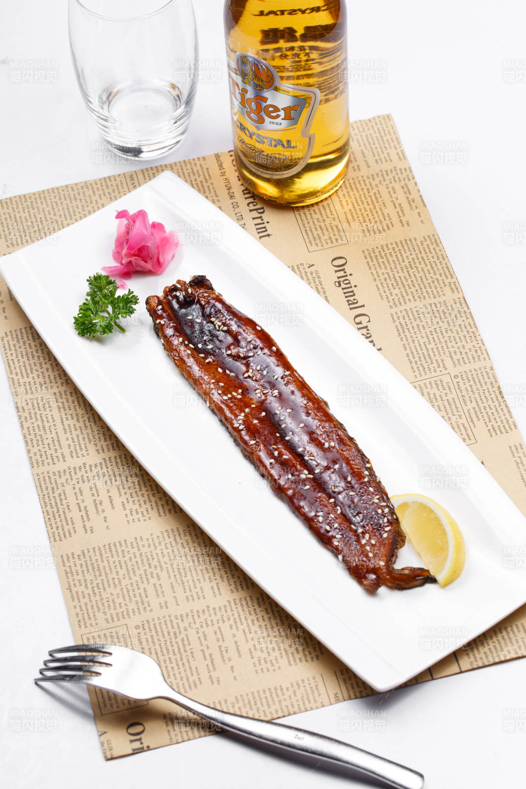 长方形瓷盘装的日式烤鳗鱼摆放在英文包装纸上图片
