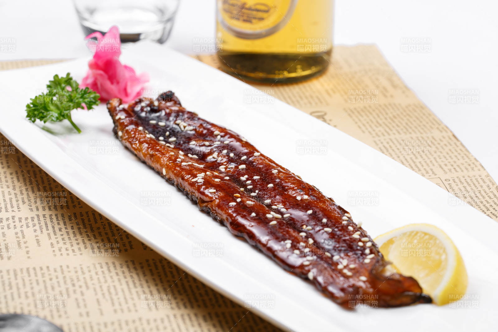 长方形瓷盘装的日式烤鳗鱼摆放在英文包装纸上图片