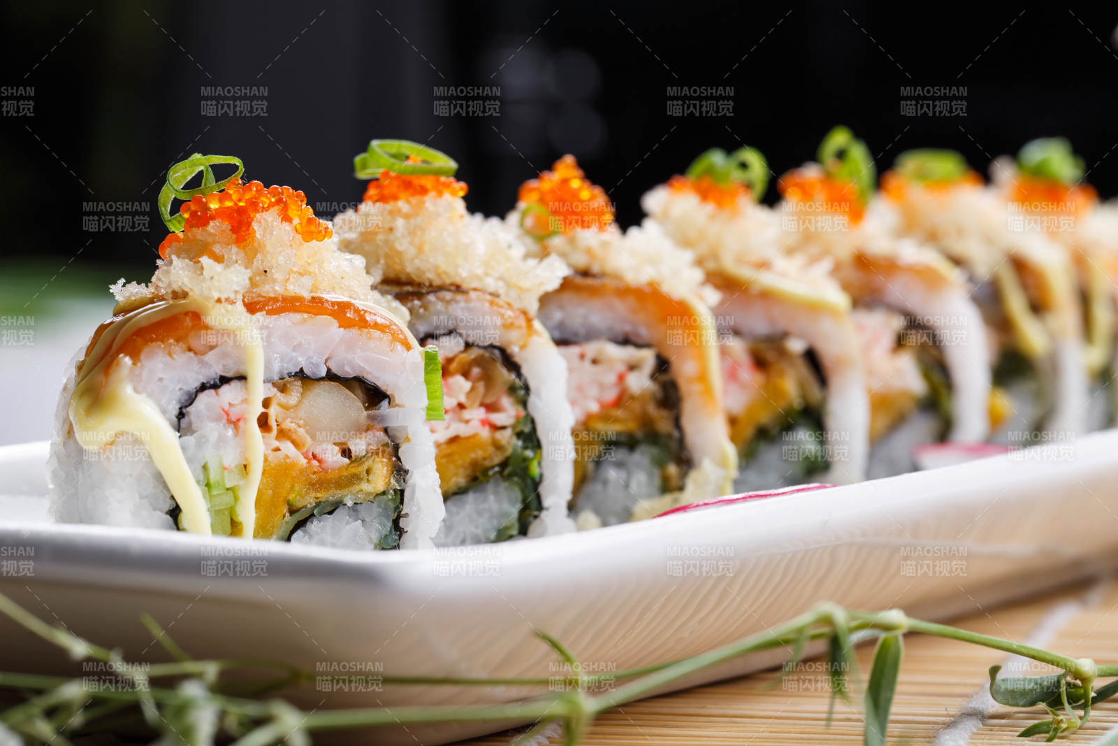 长瓷盘装的蟹籽教授卷摆放在寿司帘上图片