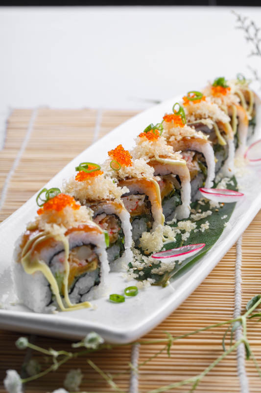 长瓷盘装的蟹籽教授卷摆放在寿司帘上图片