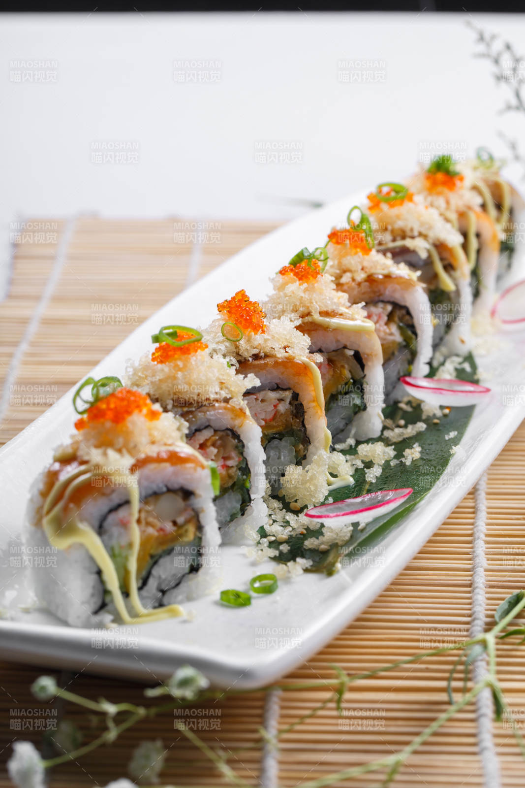 长瓷盘装的蟹籽教授卷摆放在寿司帘上图片