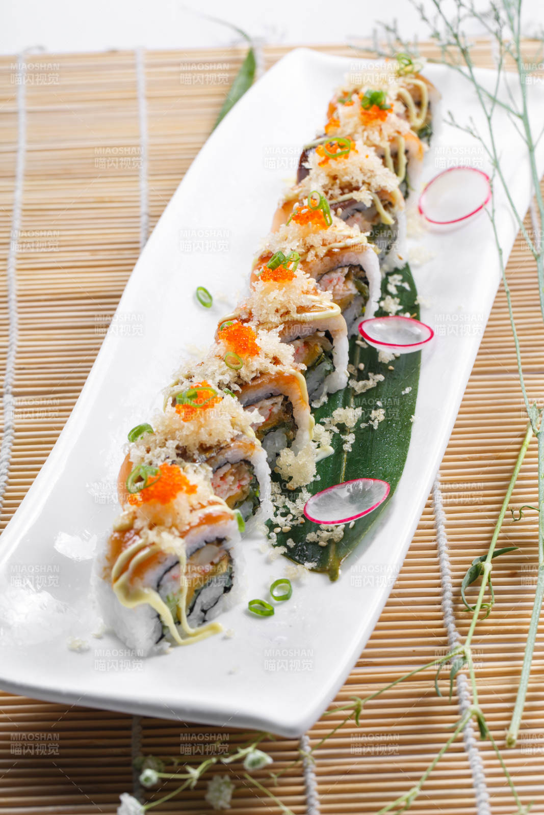 长瓷盘装的蟹籽教授卷摆放在寿司帘上图片