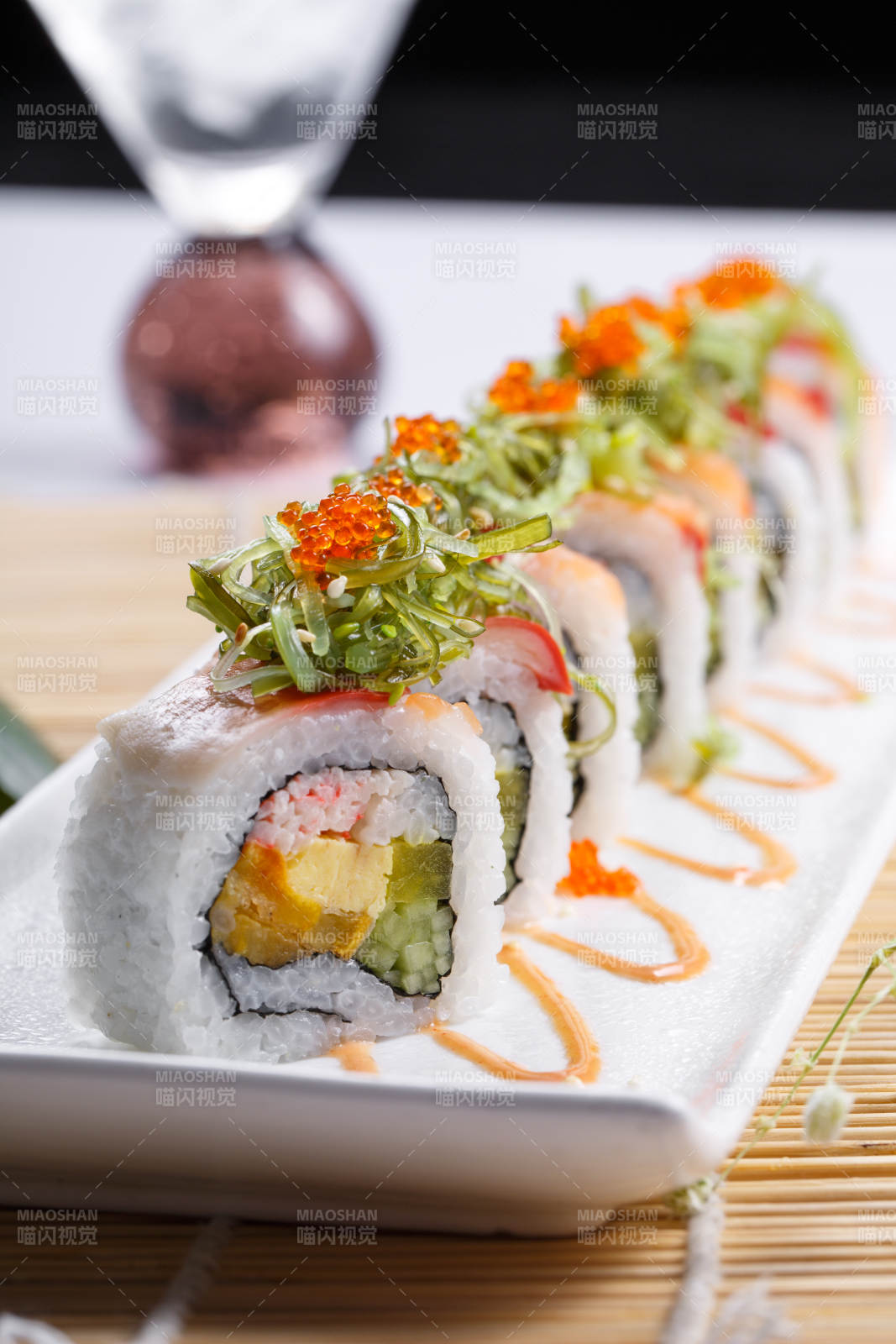 长瓷盘装的蟹籽教授卷摆放在寿司帘上图片