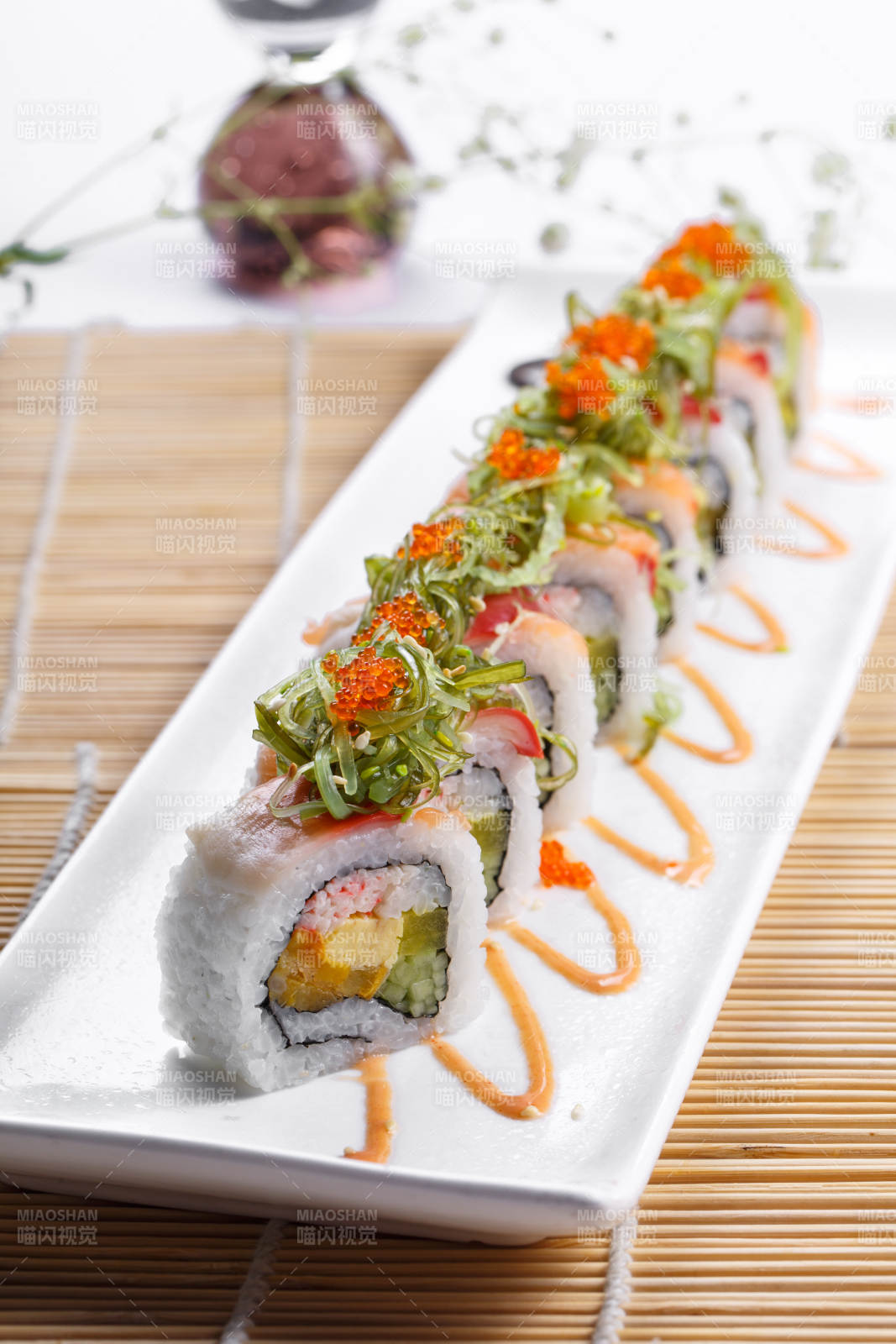 长瓷盘装的蟹籽教授卷摆放在寿司帘上图片