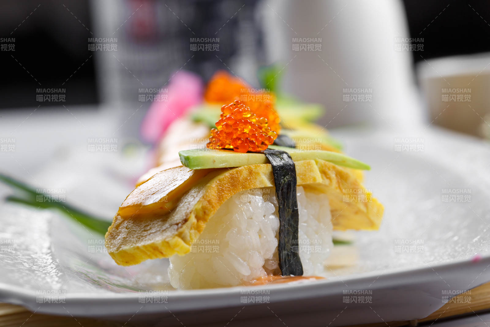 烧蛋蟹子芒果手握寿司摆放在寿司帘上图片