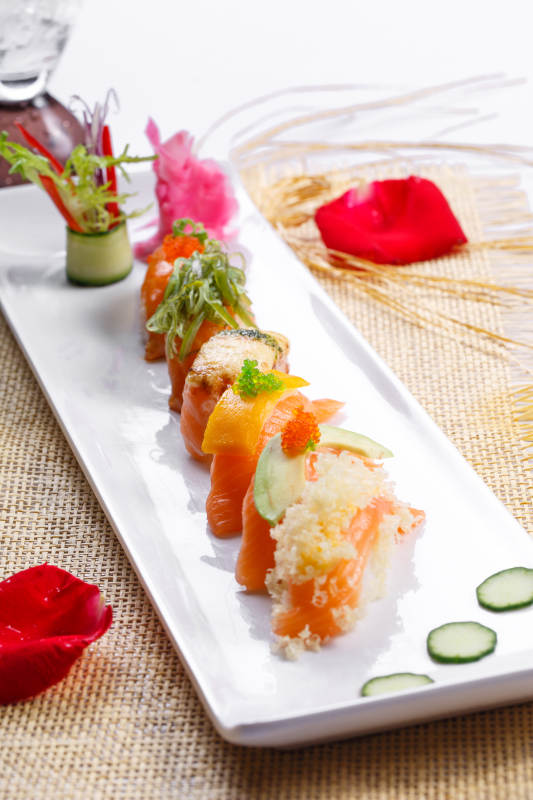 什锦三文鱼手握寿司摆放在草垫上图片