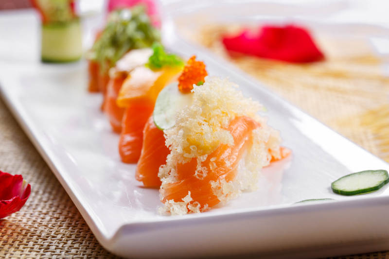 什锦三文鱼手握寿司摆放在草垫上图片